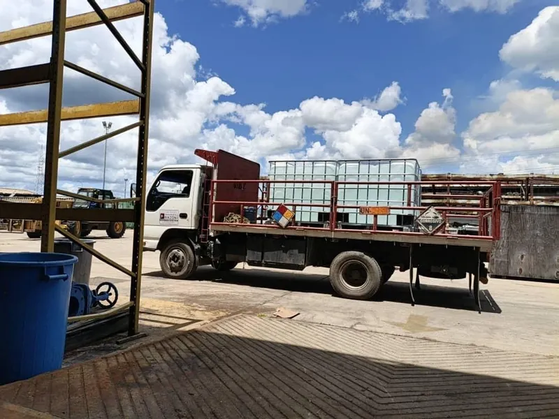 Camión con contenedores IBC sobre la plataforma, estacionado en un patio industrial